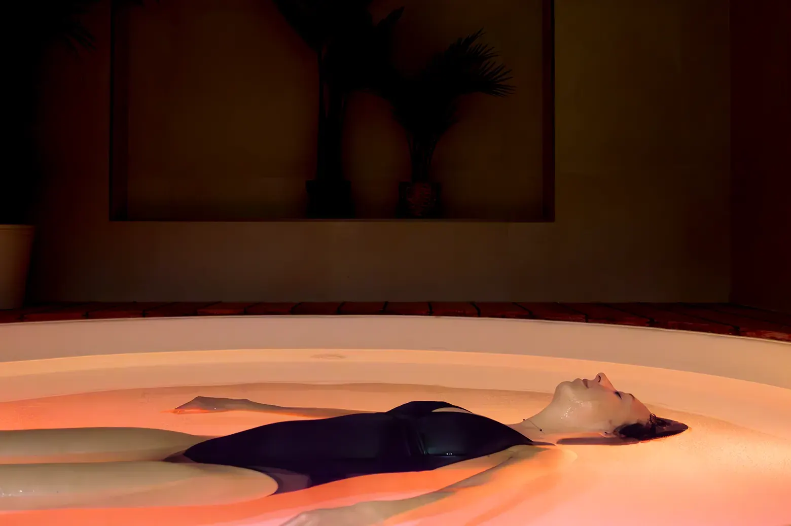 Une femme flotte, les yeux fermés, dans l'eau chaude du bassin