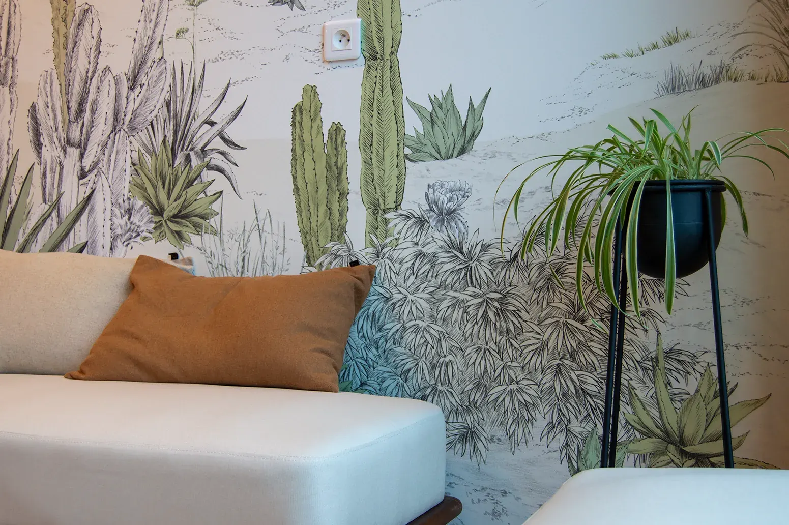 L'espace détente : canapé clair, coussin couleur argile et papier peint végétal